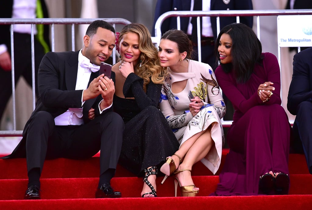 John Legend, Chrissy Teigen, Emily Ratajkowski, and Gabrielle Union were entranced by something on the singer's cell phone while sitting on the famous Met Gala steps.