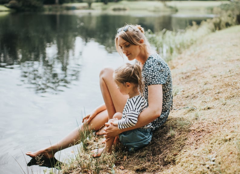 Adult and child together at the edge of a lake.