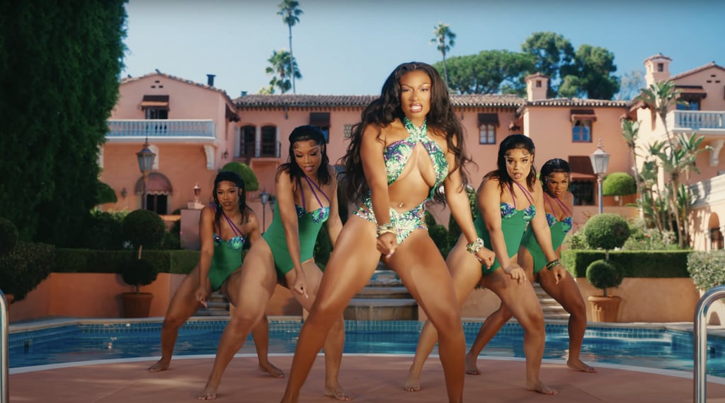 Her backup dancers coordinate in green one-piece swimsuits with purple accents.