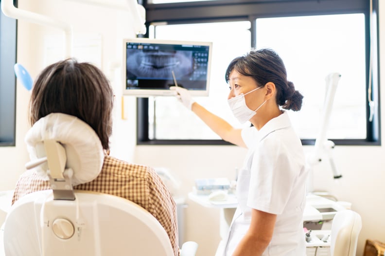A female dental doctor is showing an x-ray image and taking explanations to a patient at her medical office.