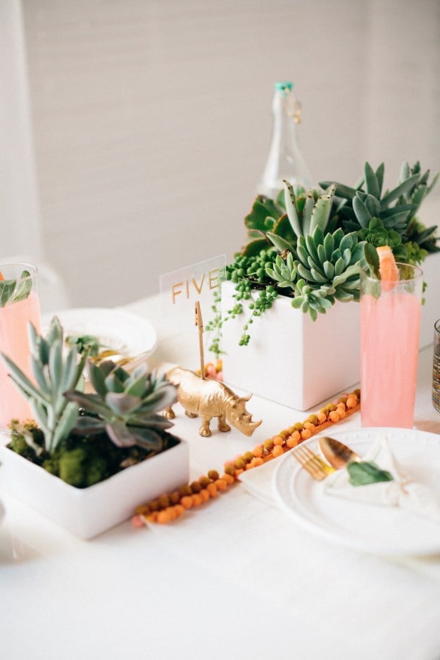 A bright pom-pom trim looks extrafestive next to succulents in modern, white pots. 
Photo by Kimberly Chau via Sugar and Cloth