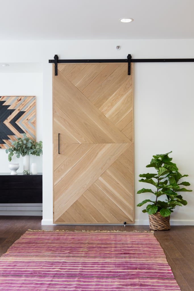 A woven pink rug sits beneath a beautifully crafted wood door that slides on a hanger.