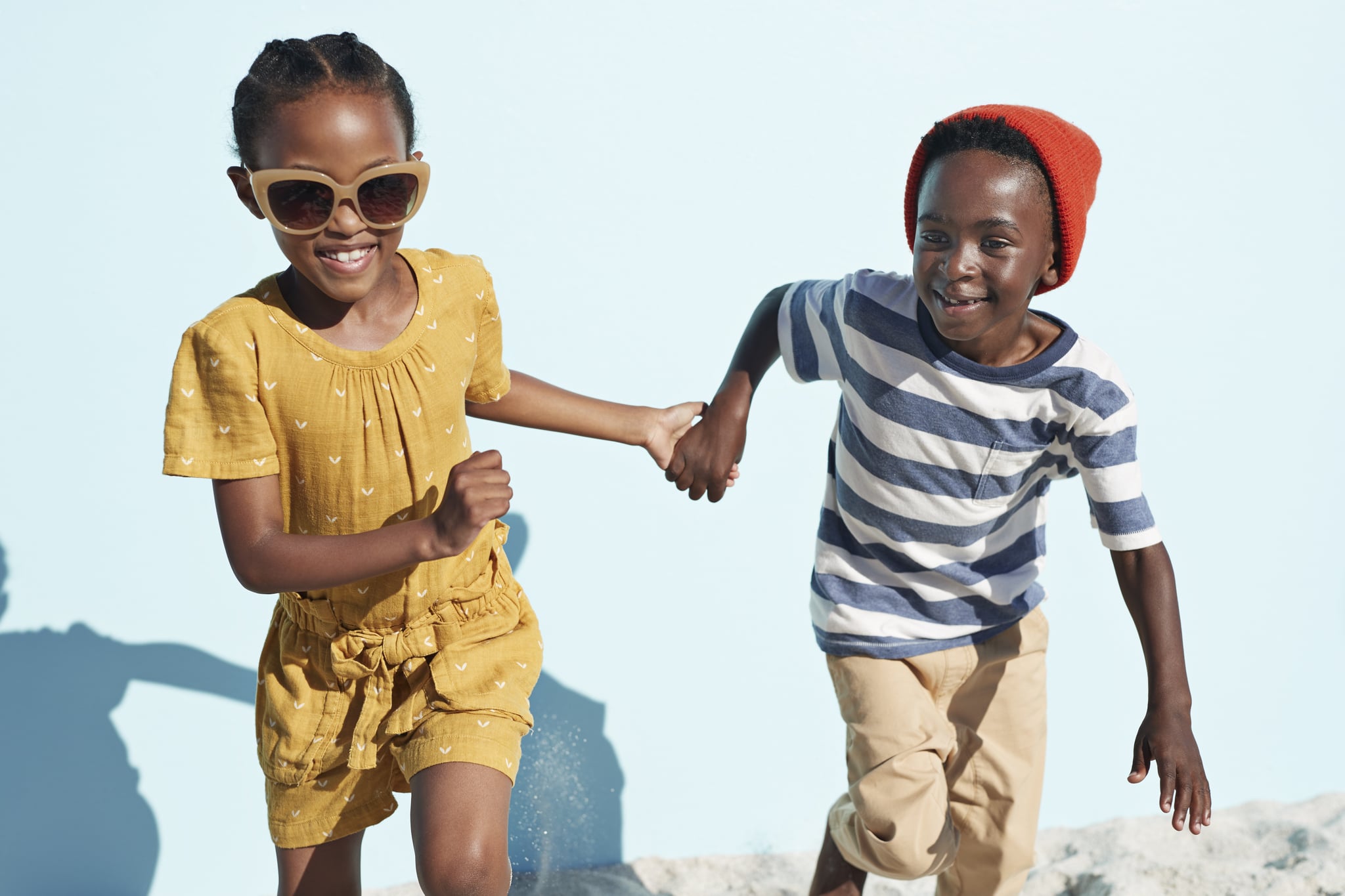 Children having joyful interaction, shot on a blue solid background on the beach in full sun