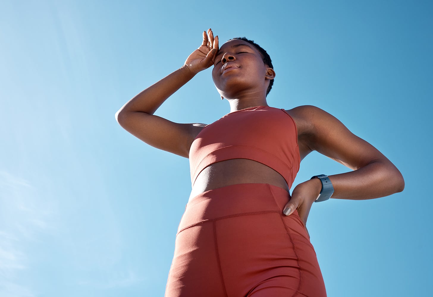 Woman wearing workout set and sweating in the sun.