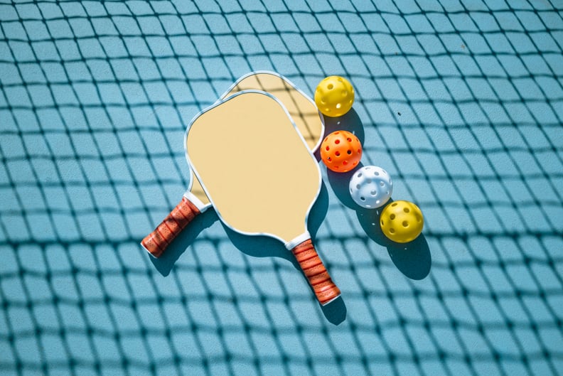 Pickleball paddles and balls are shown on a pickleball court.