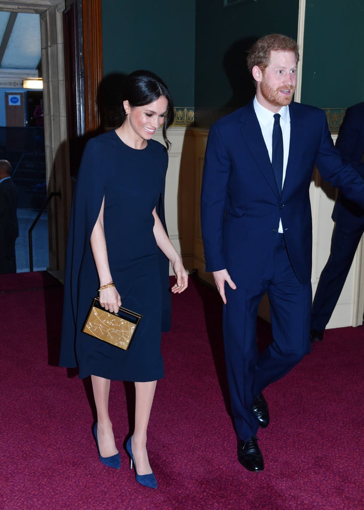 For Queen Elizabeth's 92nd birthday celebrations, Meghan stunned in a sleek and sophisticated navy blue cape dress by Stella McCartney. She accessorized it with navy suede Manolo Blahnik pumps, Isabel Marant gold hoop earrings, and her Naeem Khan zodiac evening bag in Leo.