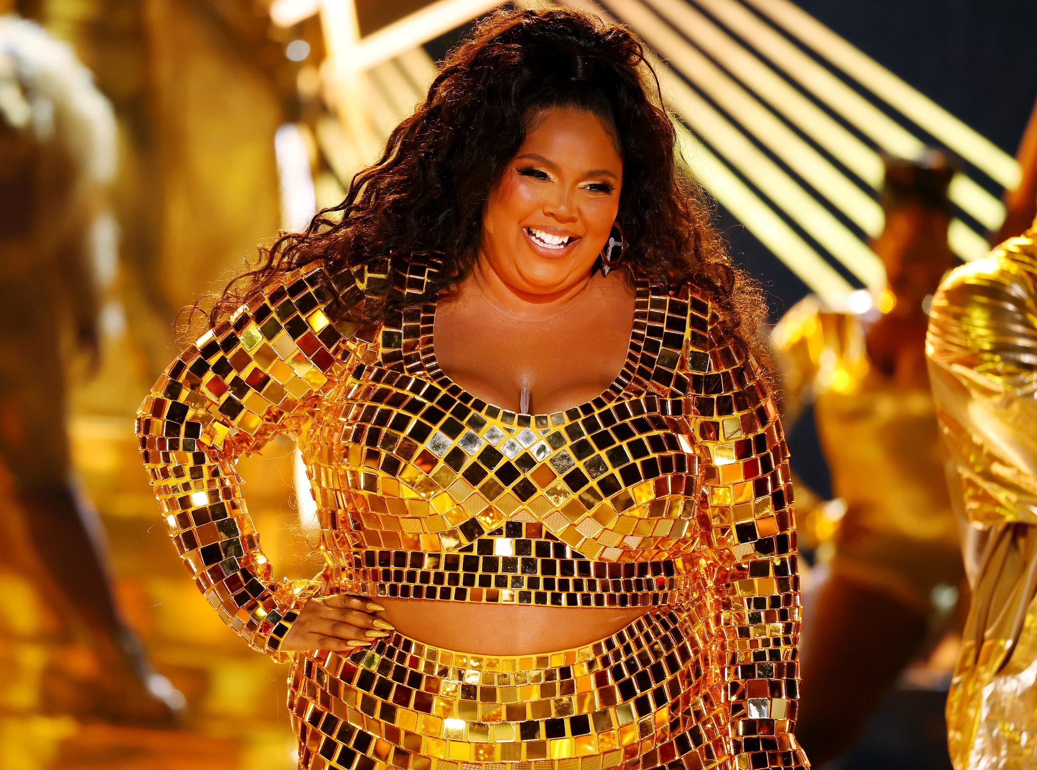 Lizzo wears golden disco ball outfit on stage and navy gown with thigh slit  on carpet at BET Awards