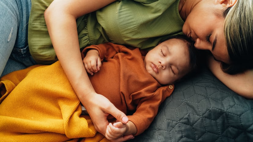 Young mother sleeping with her baby boy in bed