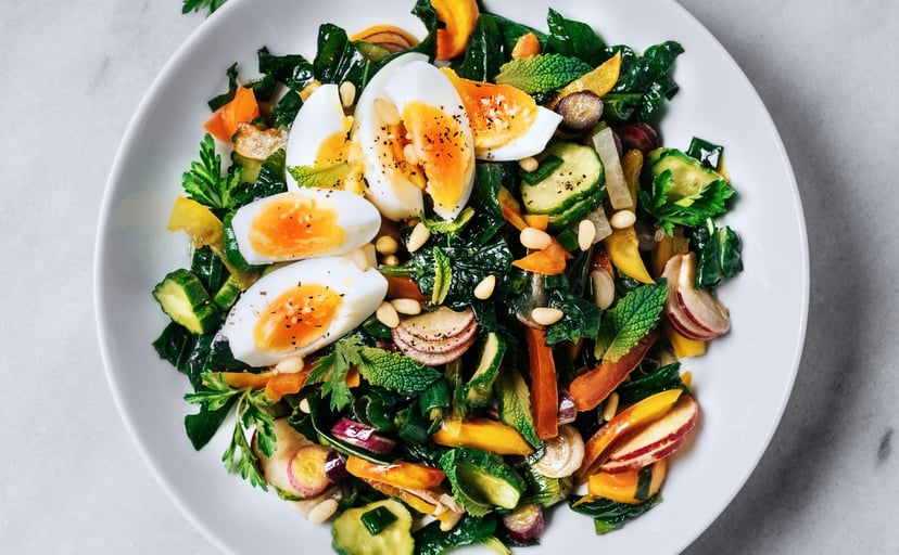 A bowl of fresh salad with boiled eggs on white background
