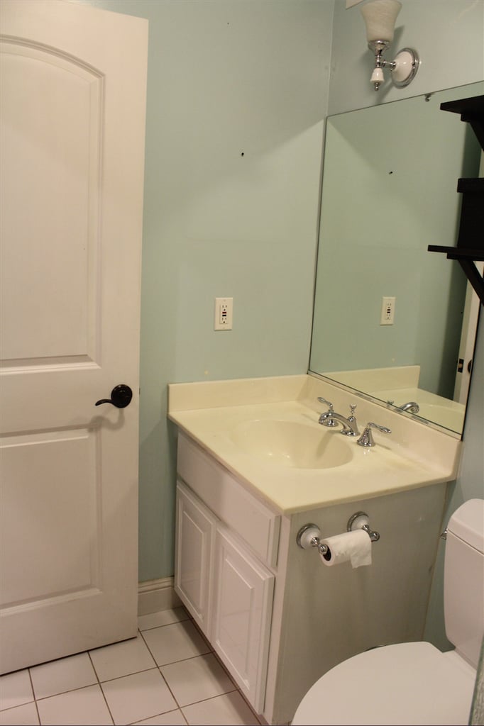 Now, a spotlight on the builder-grade accessories I loathed but did nothing about. Frosted, bell-shaped light fixture and matching toilet paper holder? Check! Large, frameless mirror? I see you. Last of all, the sink vanity with a faux top drawer. Who needs storage in a bathroom, anyway?
