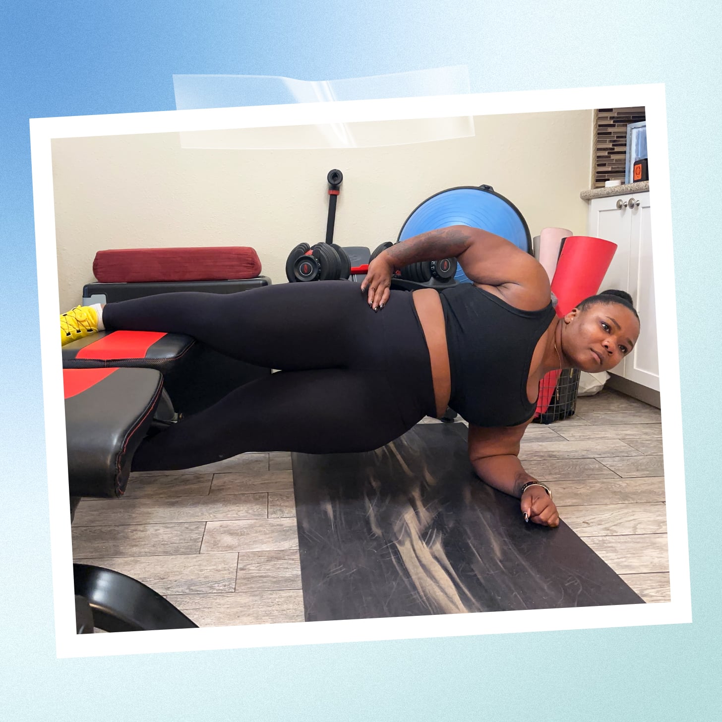 Slim woman in sportswear looking at camera while doing plank on