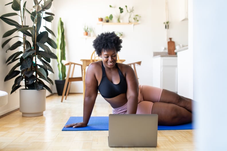 Woman in sportswear using laptop at home. Young woman searching for online exercise tutorials on a laptop at home.