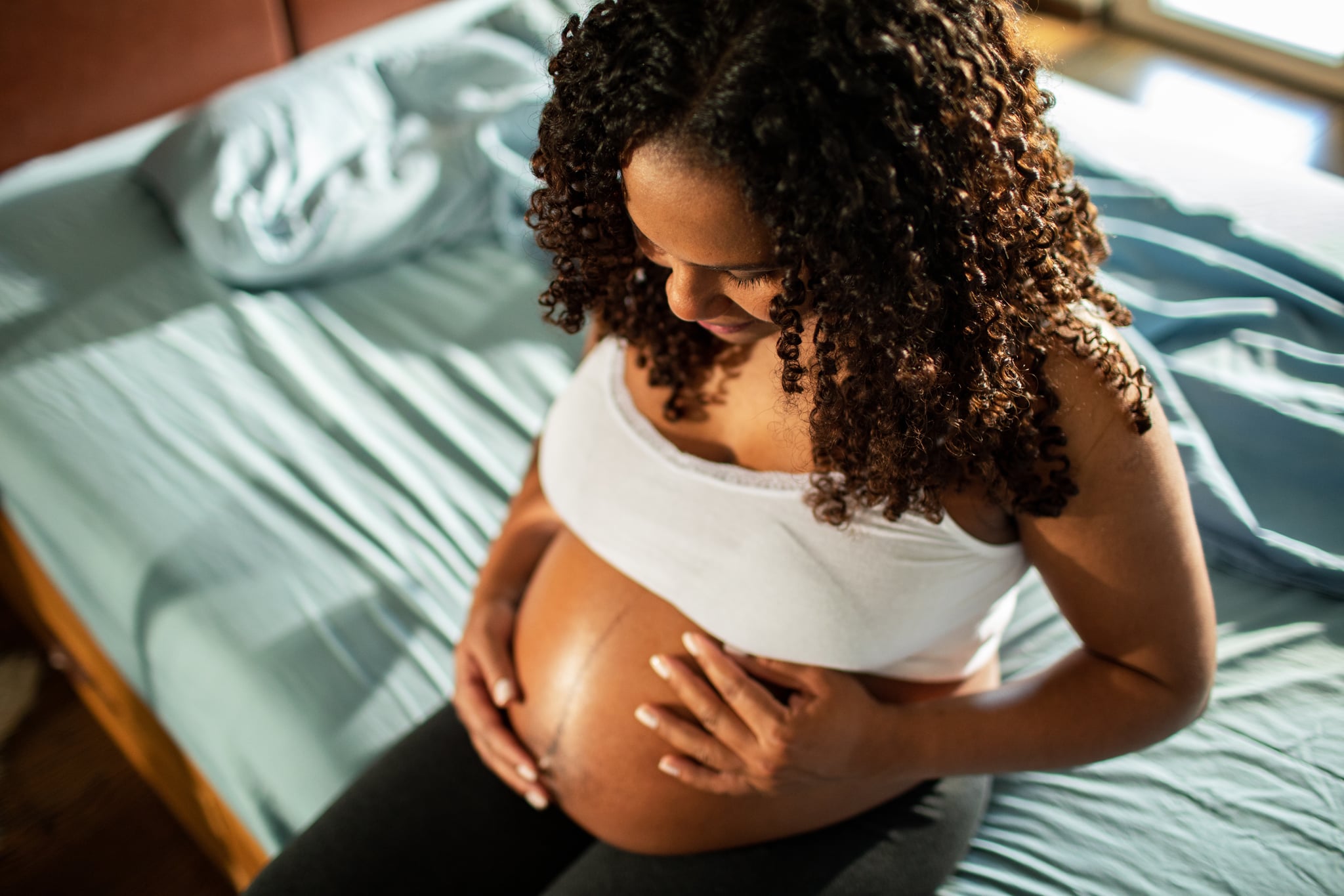 Close up of a pregnant woman holding her belly in the morning.