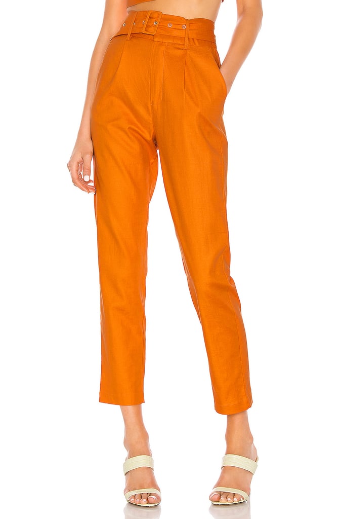 Sydne Style wears camila coehlo for revolve orange top with louis vuitton  duffel bag