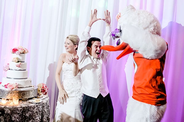 This bride surprised her groom with their college mascot just after they cut the cake — the mascot came up behind him and tapped him on the shoulder — who then got the energy back up for dancing.