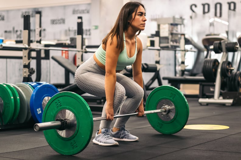 woman athlete doing deadlift in a gym. side view