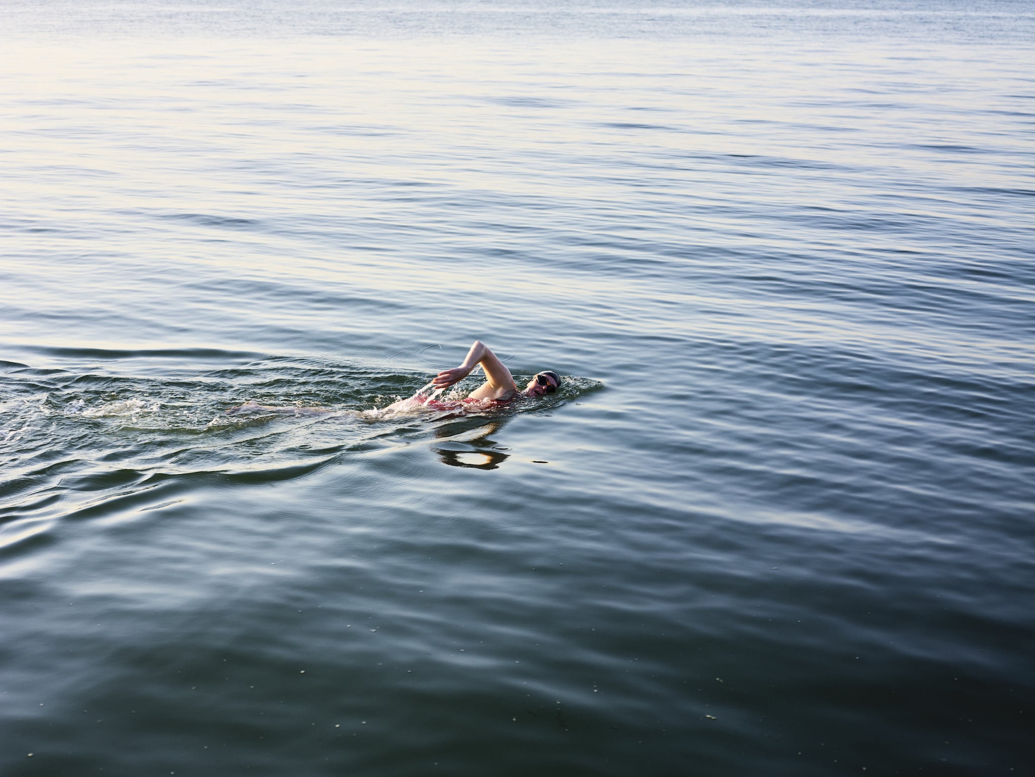 UK, Kent, Reculver, female swimmer swimming freestyle in the sea at sunset