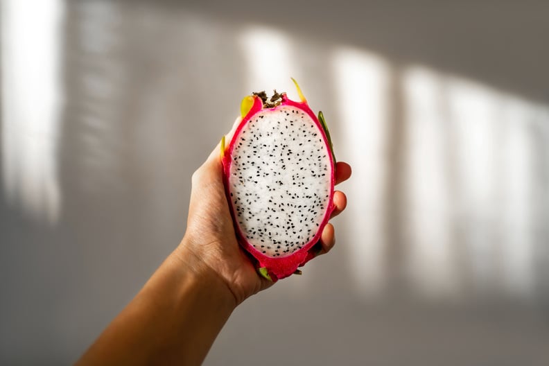 Cut dragon fruit in hand on a white background on a sunny day.