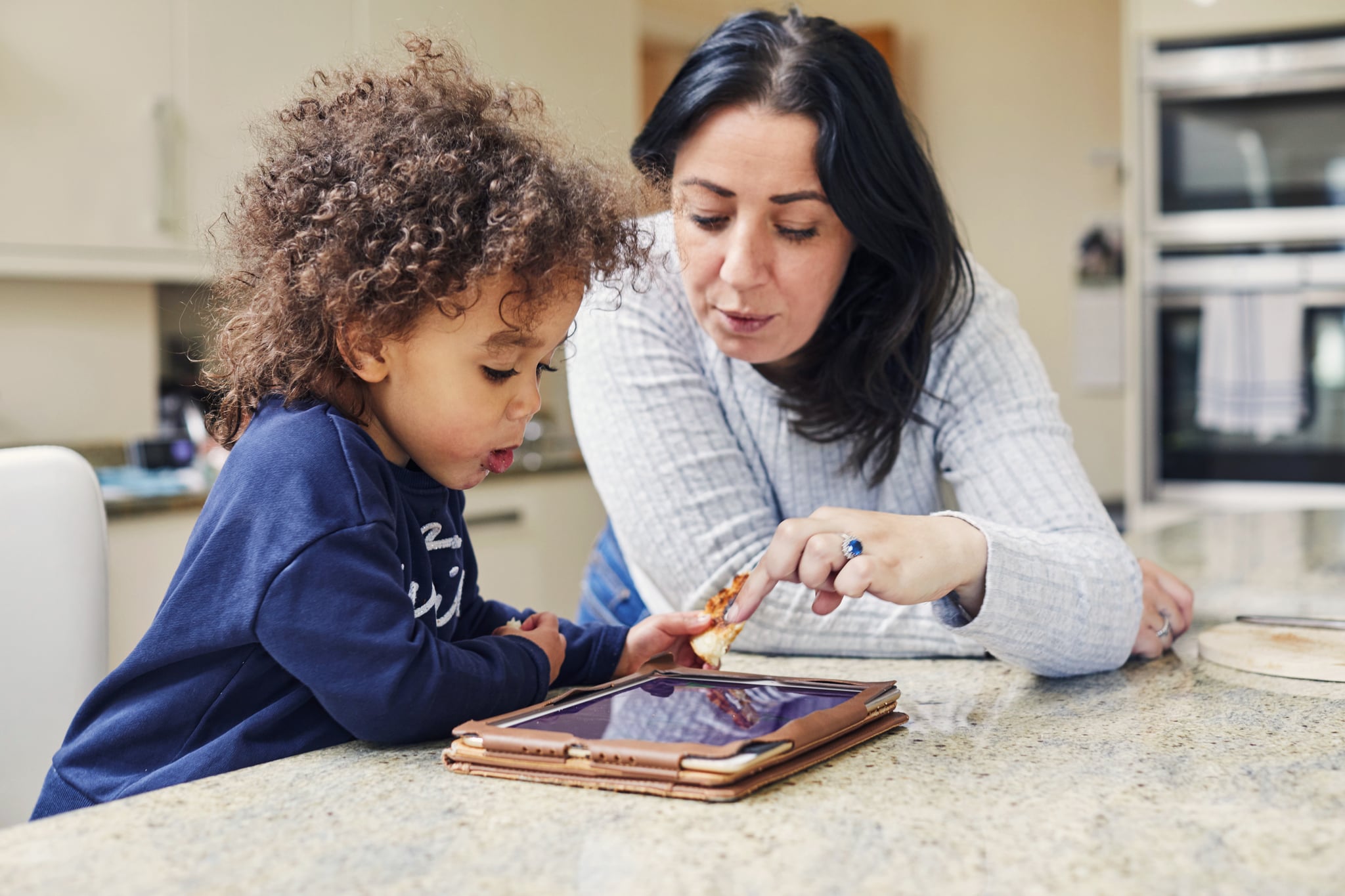 Toddler girl and mum playing with a digital tablet in the kitchen