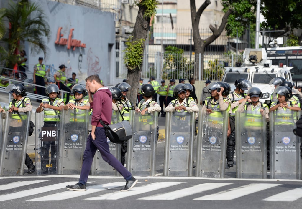 A man walks past riot police waiting for protesters on April 19, 2017.