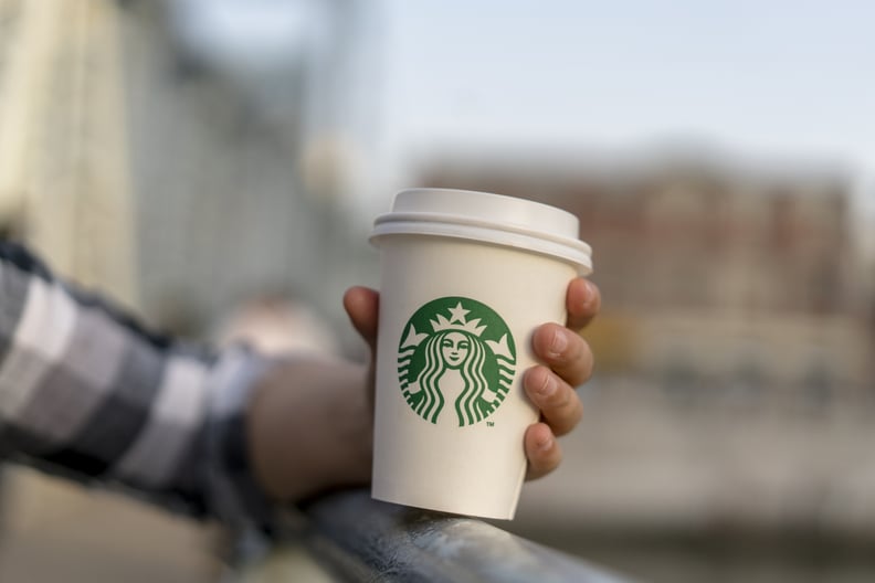 中国天津- 2017/04/29:一个女孩拥有星巴克咖啡杯的一座桥上。星巴克的杯子。据报道2017年第二季度,星巴克的收入是53亿美元,而全球的销售增长率和Sta联合