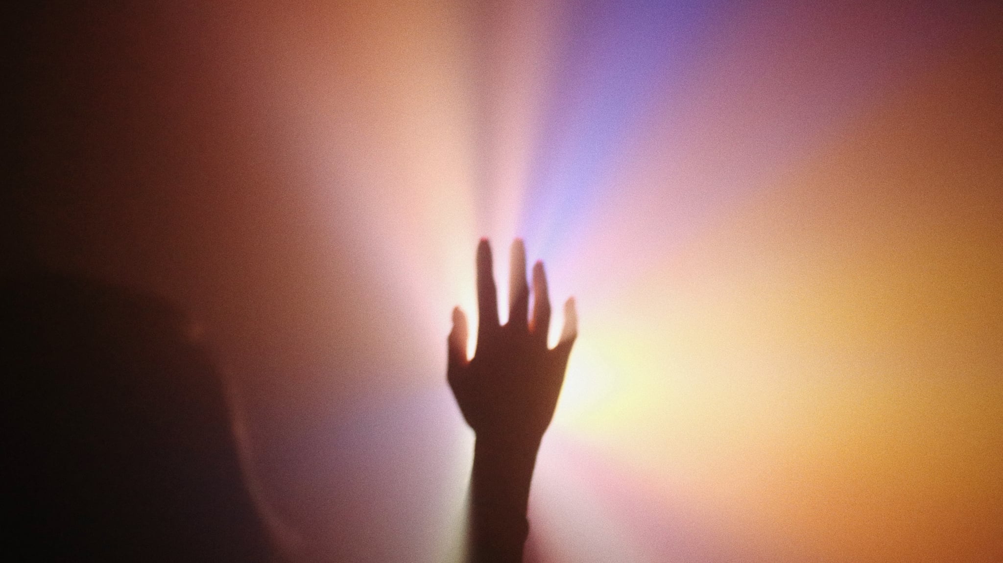 hand with rainbow lit background to symbolize the spirituality of universal year seven numerology for 2023