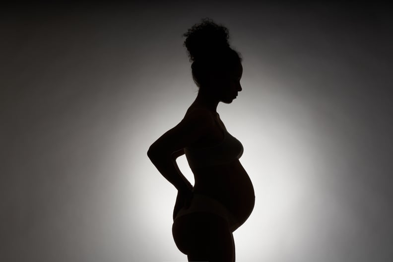 轮廓的怀孕的非洲裔妇女在白色背景副本空间。一个年轻女人的形象与卷发撞站,她的手在她的背上。母亲的概念、怀孕、背痛和分娩。