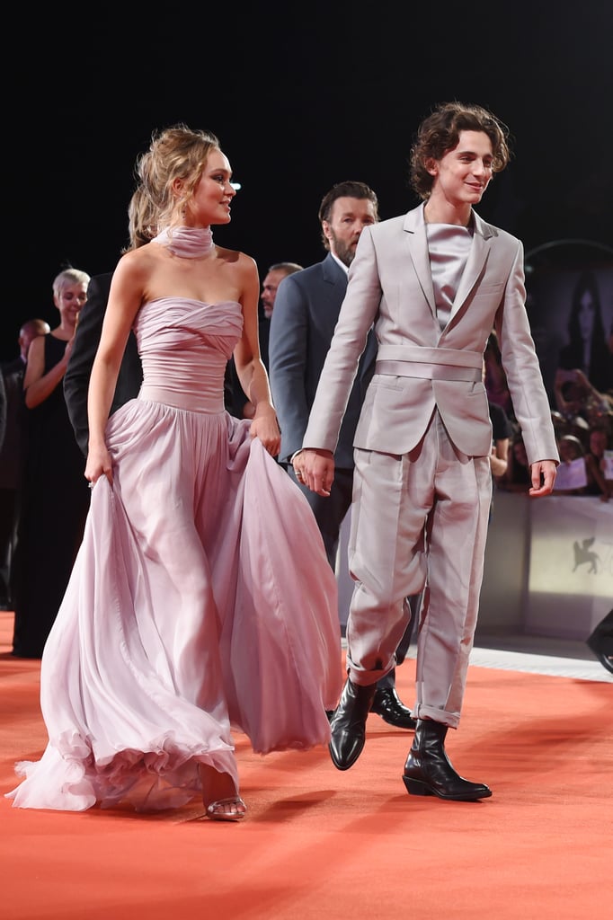 Timothée Chalamet and Lily-Rose Depp's glamorous appearance at The King world premiere will leave you bowing down — and I'm not just saying that because of the convenient pun. Wearing complementary gray outfits, the costars celebrated their forthcoming Netflix film at the 2019 Venice Film Festival on Monday. Though Timothée and Lily were reportedly dating as of Oct. 2018, the two appeared to keep it strictly professional on the red carpet.
Timothée and Lily, who portray Henry V and Catherine of Valois in the film, were joined by their costars Joel Edgerton, Ben Mendelsohn, Tom Glynn-Carney, Sean Harris, and director David Michod. Fortunately Robert Pattinson, who portrays Louis, Duke of Guyenne, was unable to attend, for that might have been too much to handle. See the royally stunning shots of Timothée and Lily ahead.