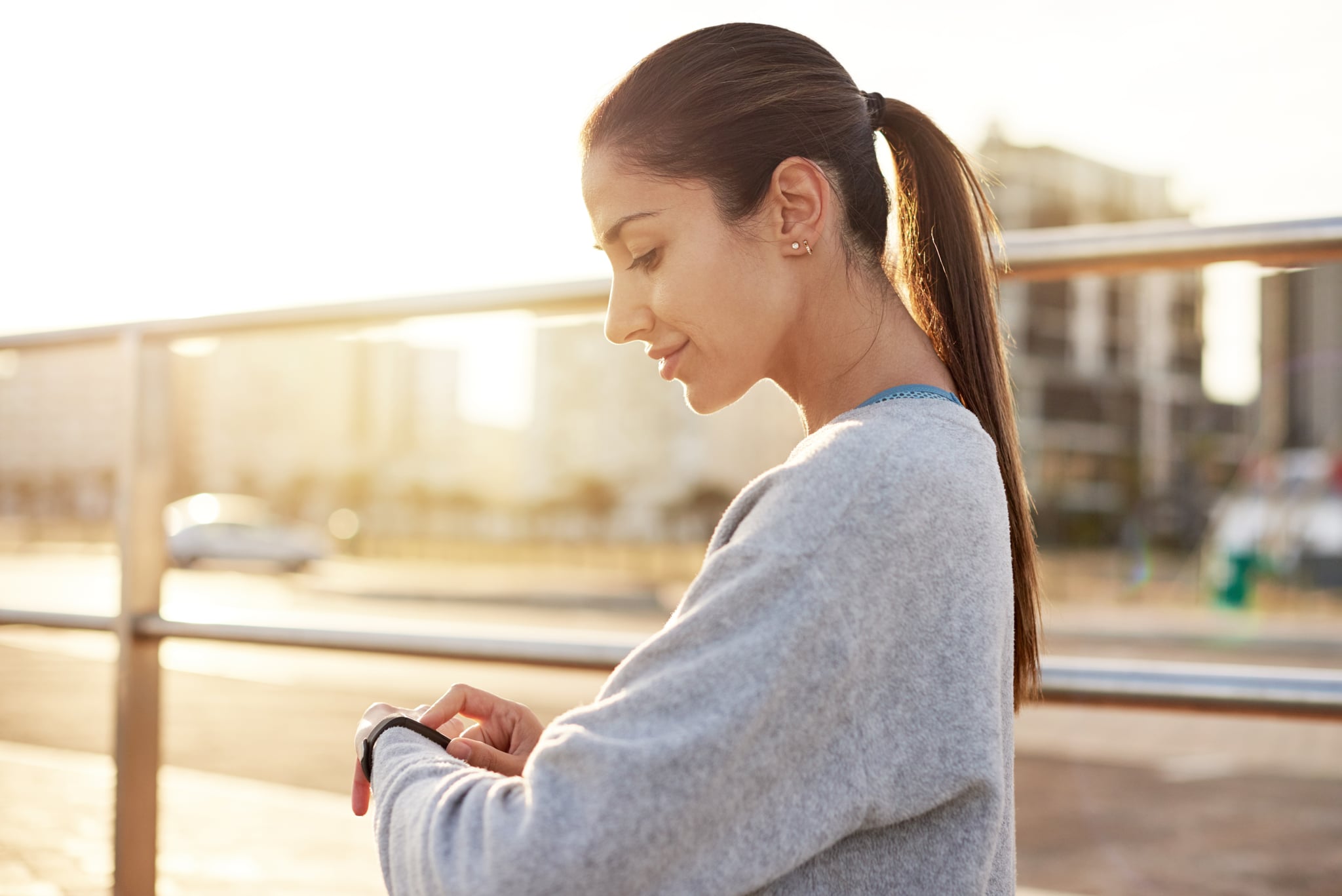 Shot of a sporty young woman checking her watch while exercising outdoors