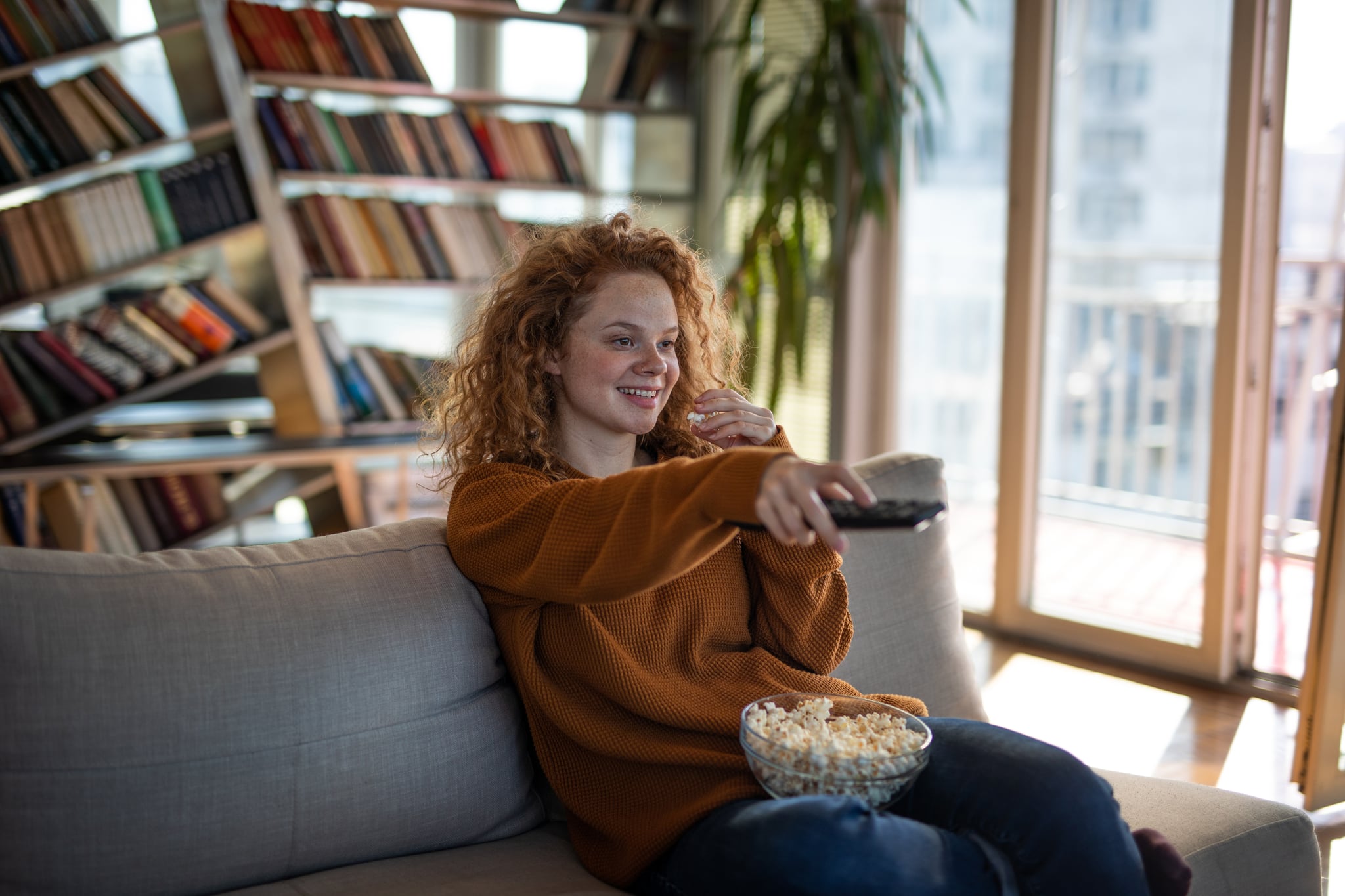 Young beautiful woman eating popcorn and watching movie