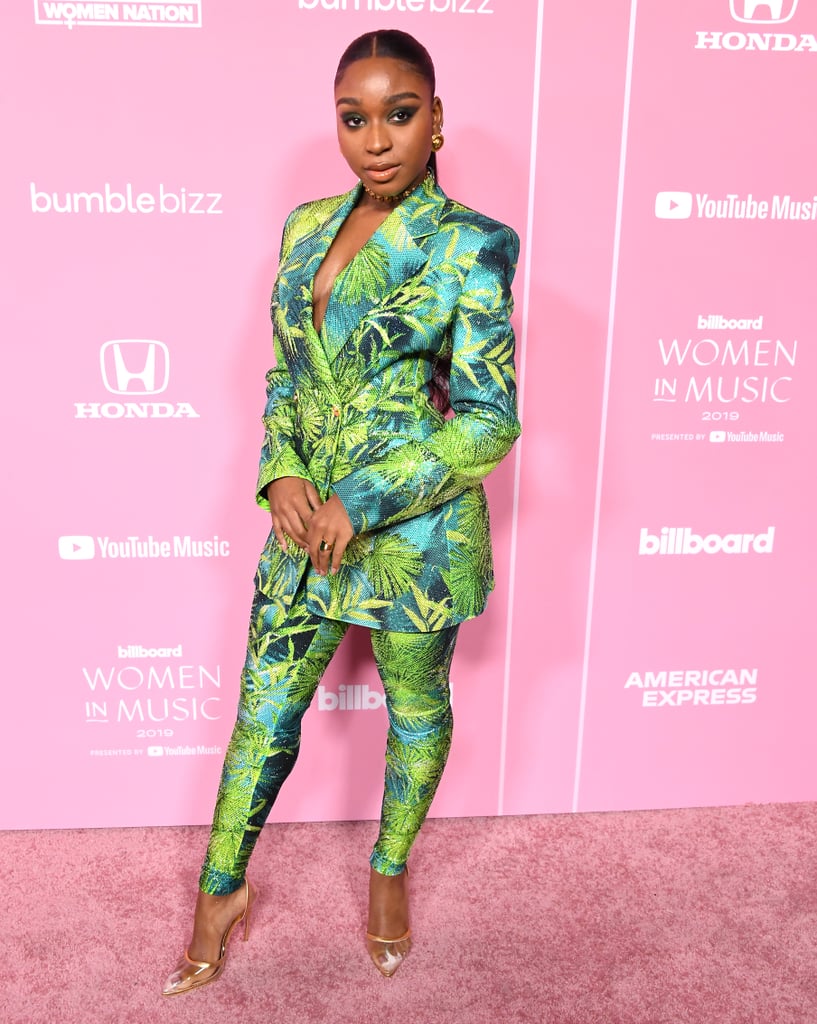 Normani just wore one of the most instantly recognizable prints in existence. The singer attended the 2019 Billboard Women in Music event on Thursday wearing an embellished Versace suit in the same palm print previously made famous by Jennifer Lopez at the 2000 Grammys, then again at the brand's Spring 2020 runway show during Milan Fashion Week. 
But back to Normani: it takes confidence to wear such an iconic print, and she certainly delivered. Her suit consisted of a double-breasted blazer and tapered skin-tight pants, which she accessorized with trendy vinyl heels, chunky gold jewelry, and a green statement ring by Ammanii. 
To say it's been a breakout year for the former Fifth Harmony member would be an understatement. After going viral for her nostalgic "Motivation" music video, Normani delivered her first solo performance during the MTV Video Music Awards, then appeared in Rihanna's lingerie show. (She's since been announced as a Savage x Fenty global brand ambassador.) See pictures of her latest memorable red carpet look ahead, and enjoy a few photos of J Lo wearing the print over the years.