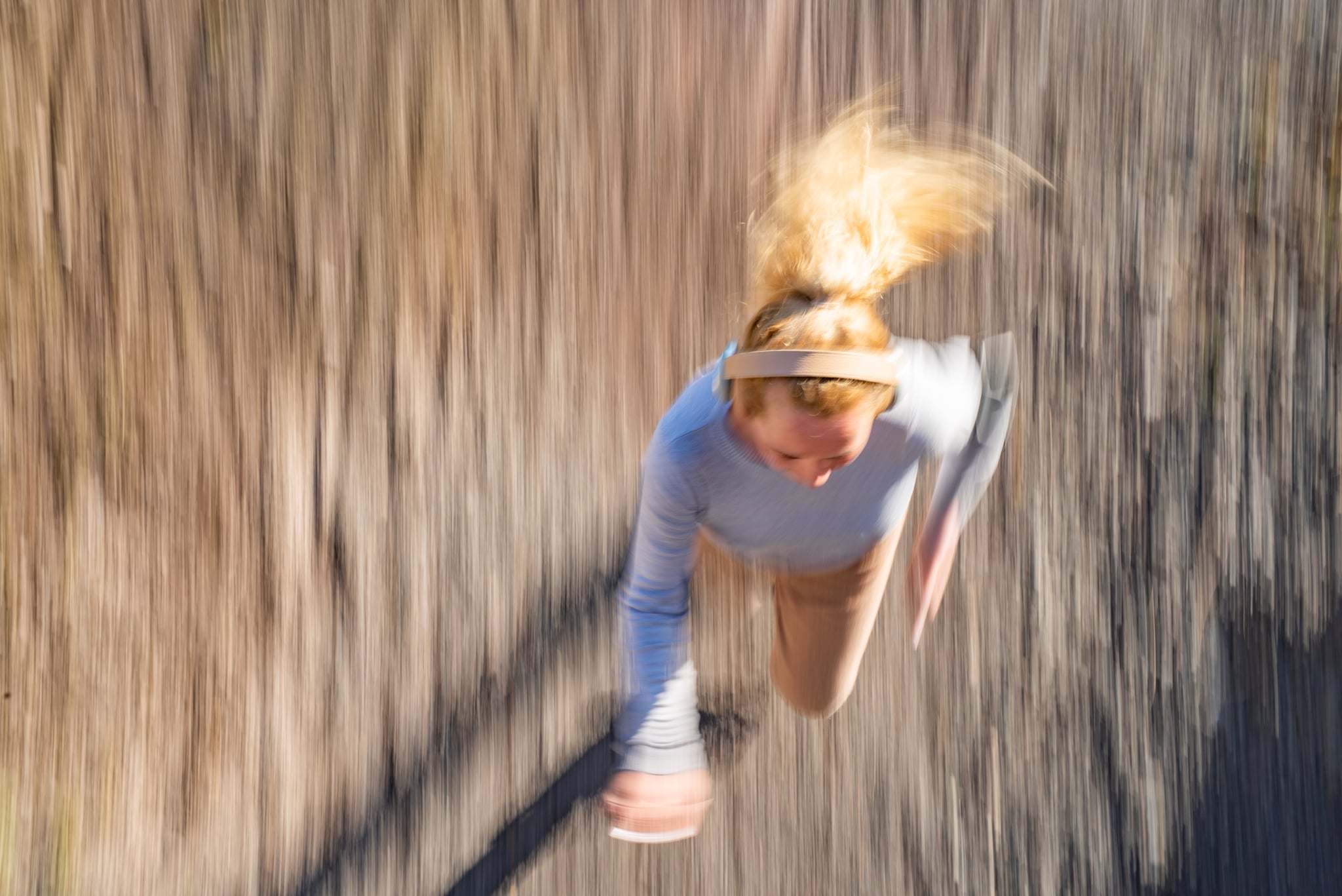 Blurred motion of a young woman jogging outdoors.