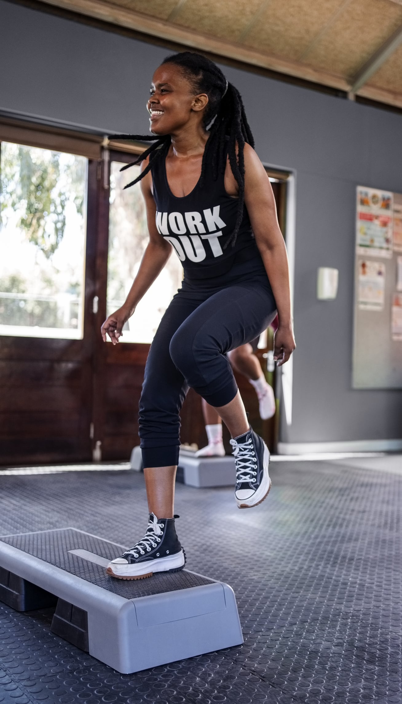 Happy young woman exercising on step aerobics equipment at gym