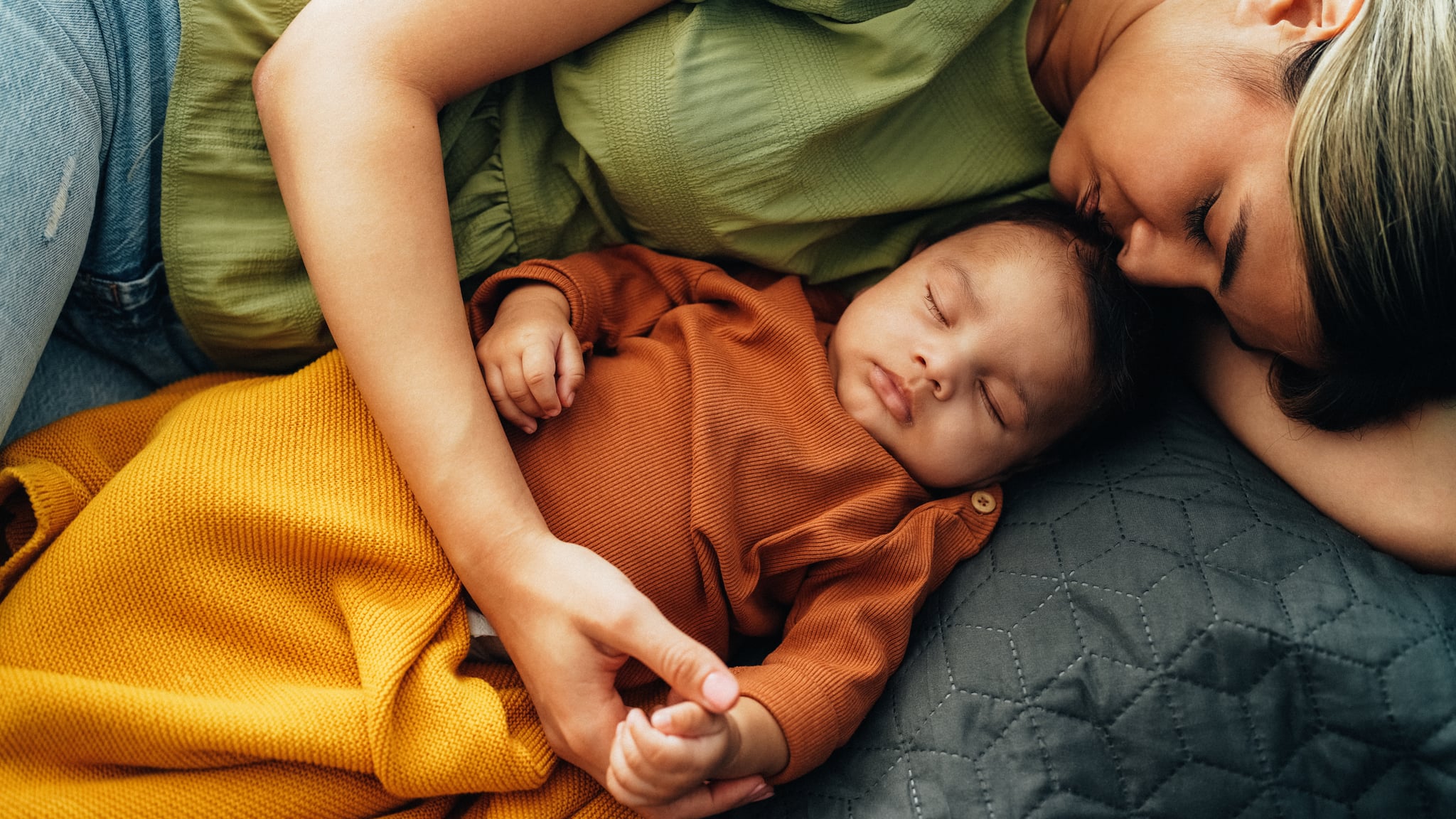 Young mother sleeping with her baby boy in bed