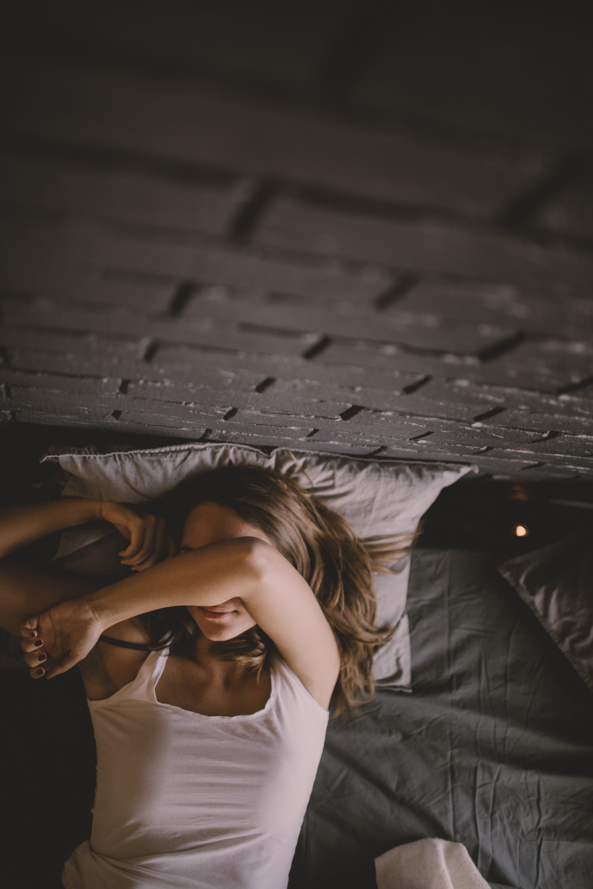 Photo of a young woman lying down in bed in her bedroom, enjoying perks of her single life