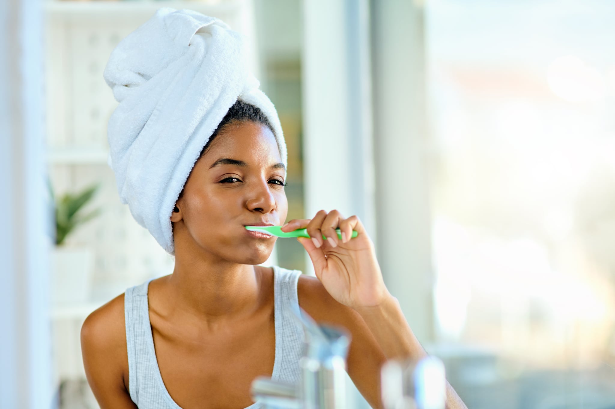 Shot of an attractive young woman brushing her teeth in the bathroom at home