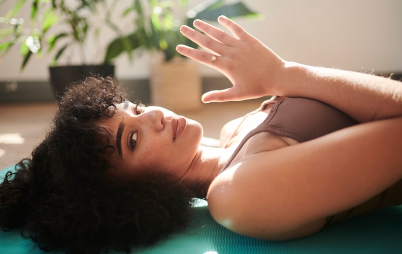 Woman Laying Flat on Her Back In Yoga Studio Holding Hands in a Prayer Pose