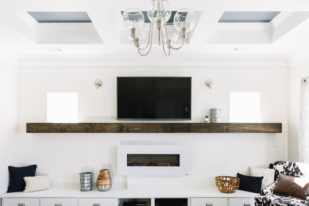 For the room's focal point, Monica installed a whopping 16-foot mantel and electric fireplace. Above it, she mounted the homeowner's flat-screen TV framed by a pair of glass lighting pendants ($40). Below, she designed a DIY seating area complete with accents like pillows, baskets, and lanterns ($29).