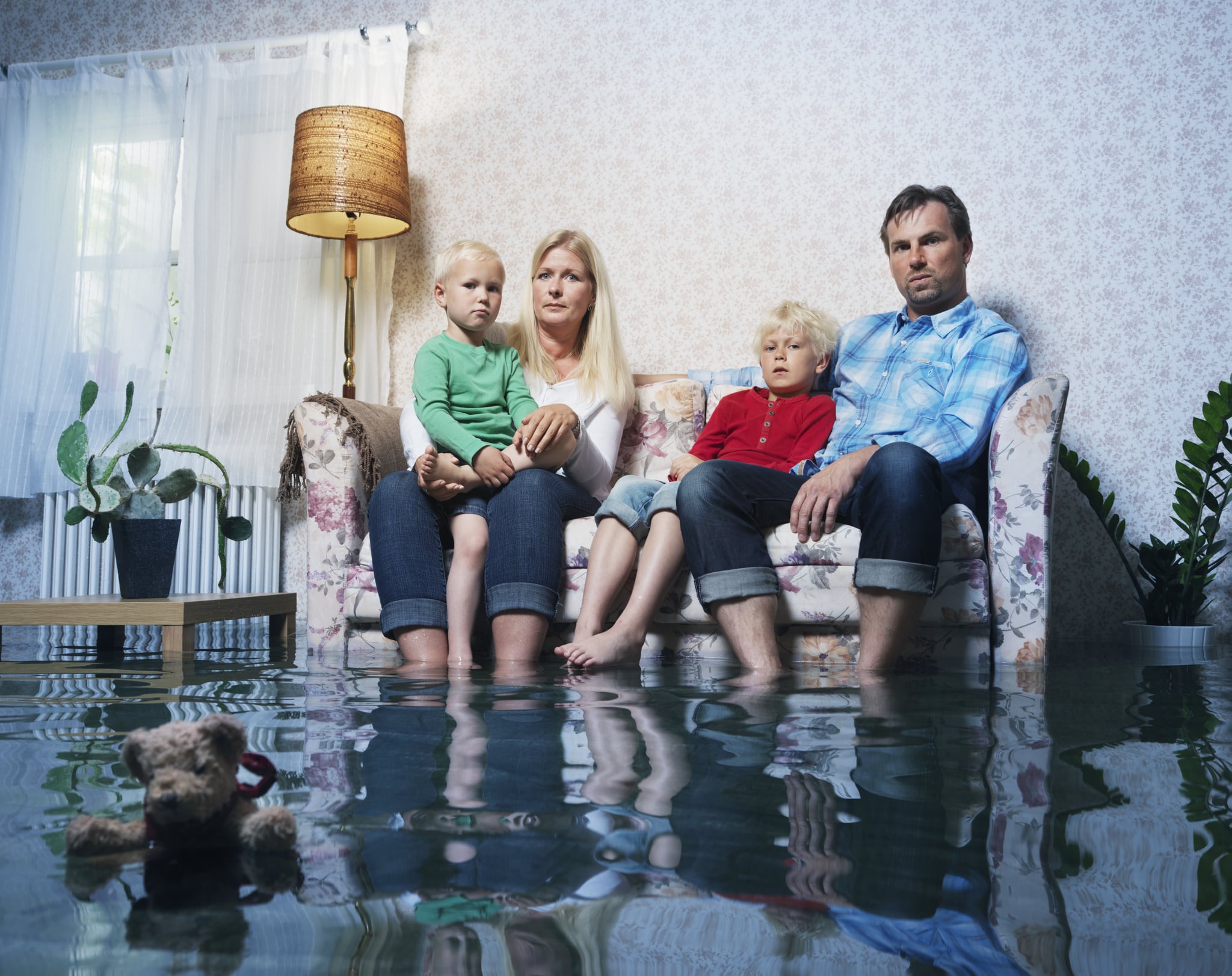portrait of family in sofa in flooded living room, not happy