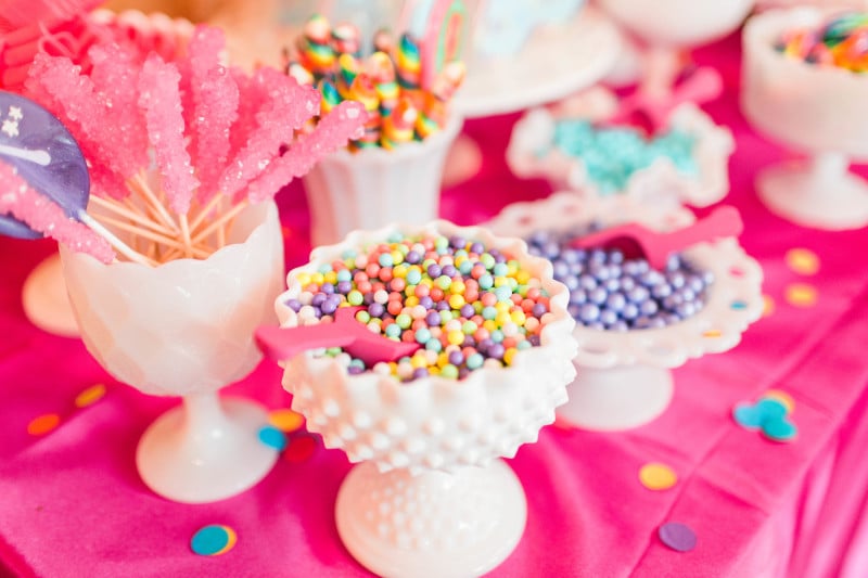 A candy bar can get expensive quick when you are using clear apothecary jars and glass vessels. No doubt they are pretty, but you’re usually left with uneaten candy that cost you a fortune. I pulled from my milk glass collection to set a small table of assorted candies. We didn’t have gobs and gobs of candies, but just enough to fill each container and set a colorful sweets station.