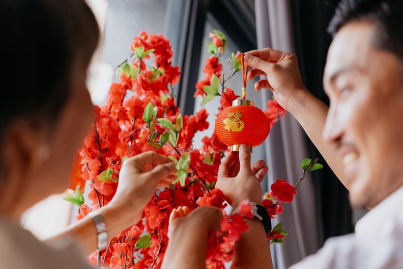 Asian Chinese mother and son hanging chinese lantern on plum tree decoration and preparing for Chinese New Year family reunion.