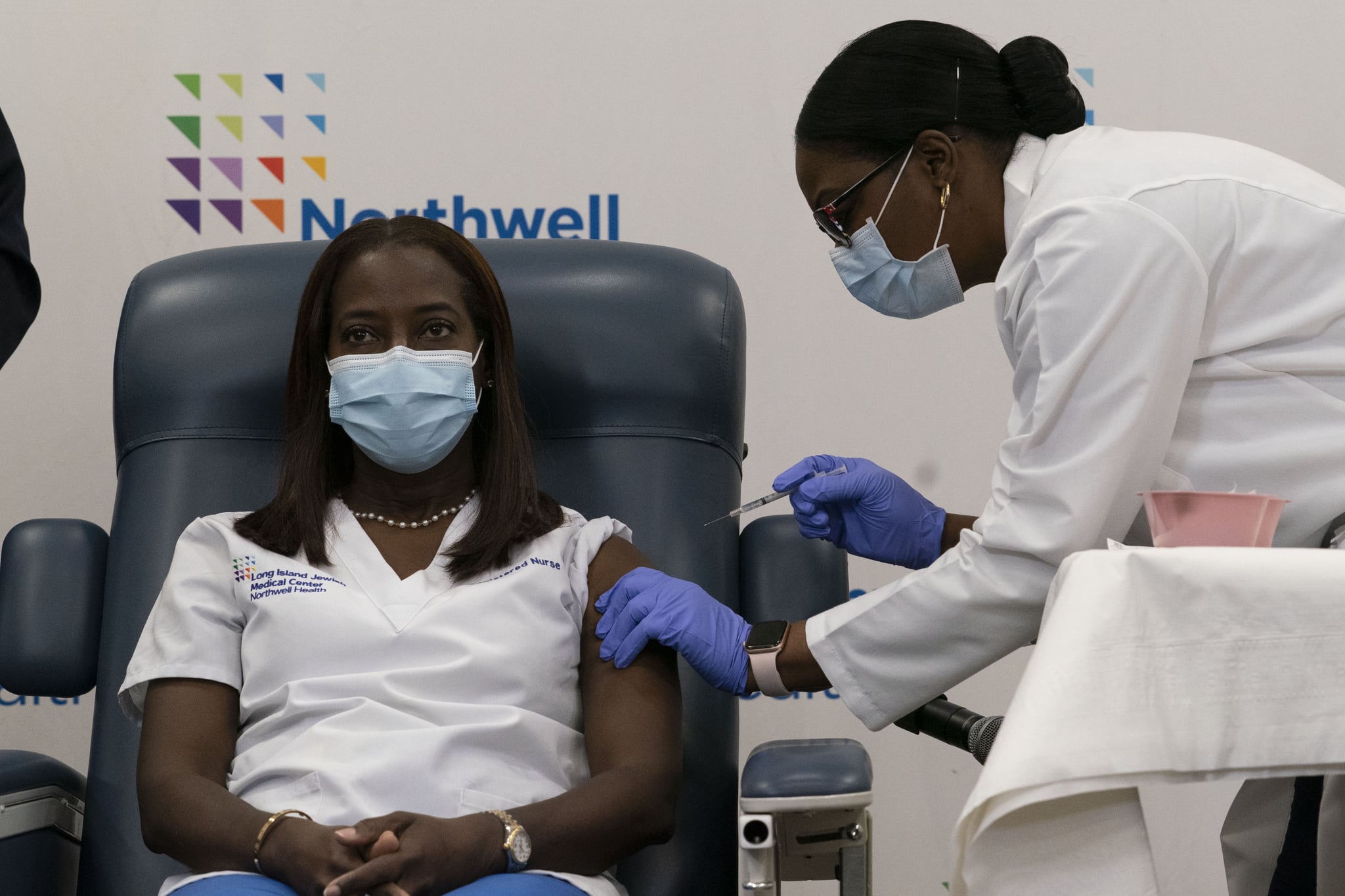 Sandra Lindsay(L), a nurse at Long Island Jewish Medical Center, is inoculated with the Covid-19 vaccine by Dr. Michelle Chester, at Long Island Jewish Medical Center, on December 14, 2020 in the Queens borough of New York. - The rollout of the Pfizer and BioNTech vaccine, the first to be approved by the Food and Drug Administration, ushers in the biggest vaccination effort in US history. More than 299,000 Americans have been killed by the virus, including over 35,000 residents of New York state. (Photo by Mark Lennihan / POOL / AFP) (Photo by MARK LENNIHAN/POOL/AFP via Getty Images)