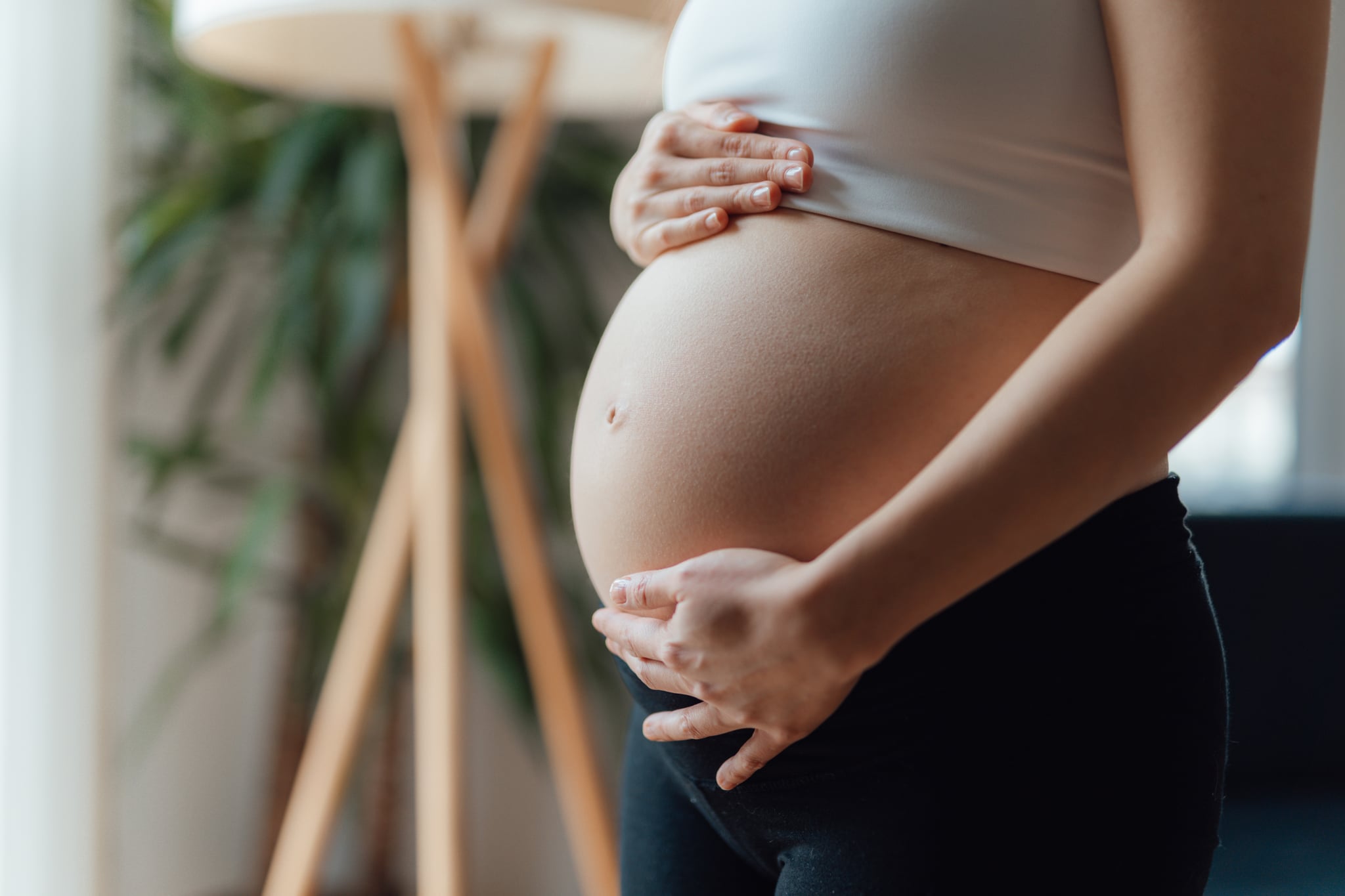 Side view close-up of pregnant woman touching her belly. Pregnancy health & wellbeing concept.