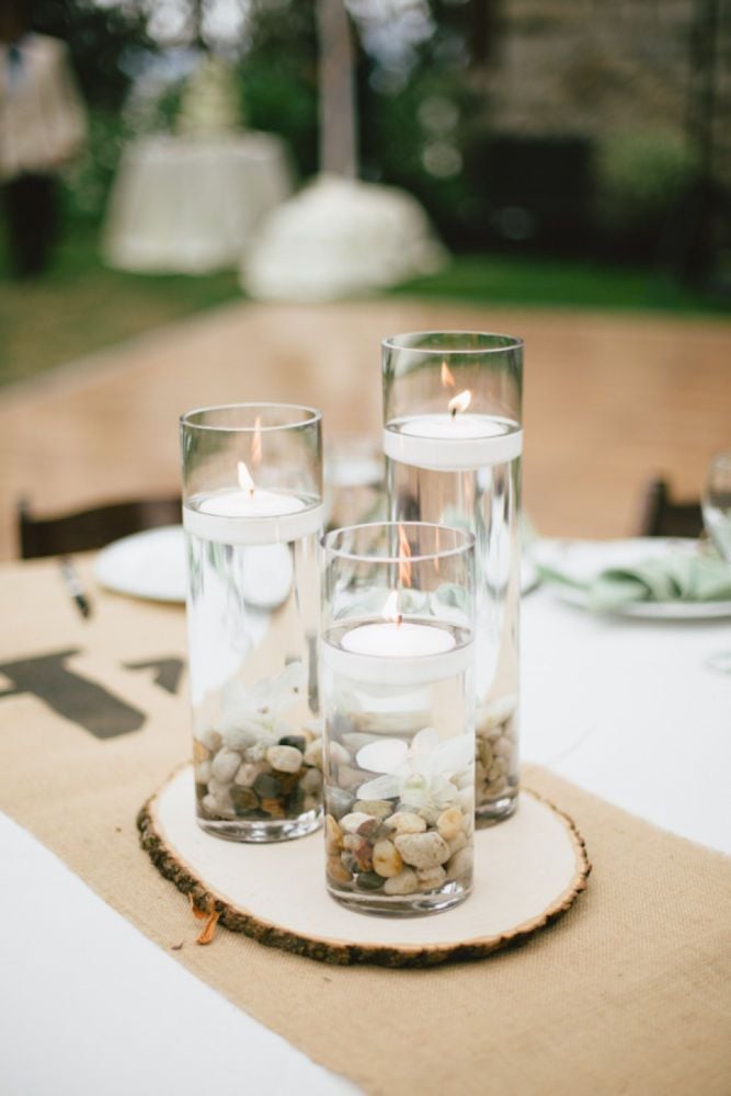 For a pretty table centerpiece, place pebbles in a glass, fill with water, and add in floating candles.