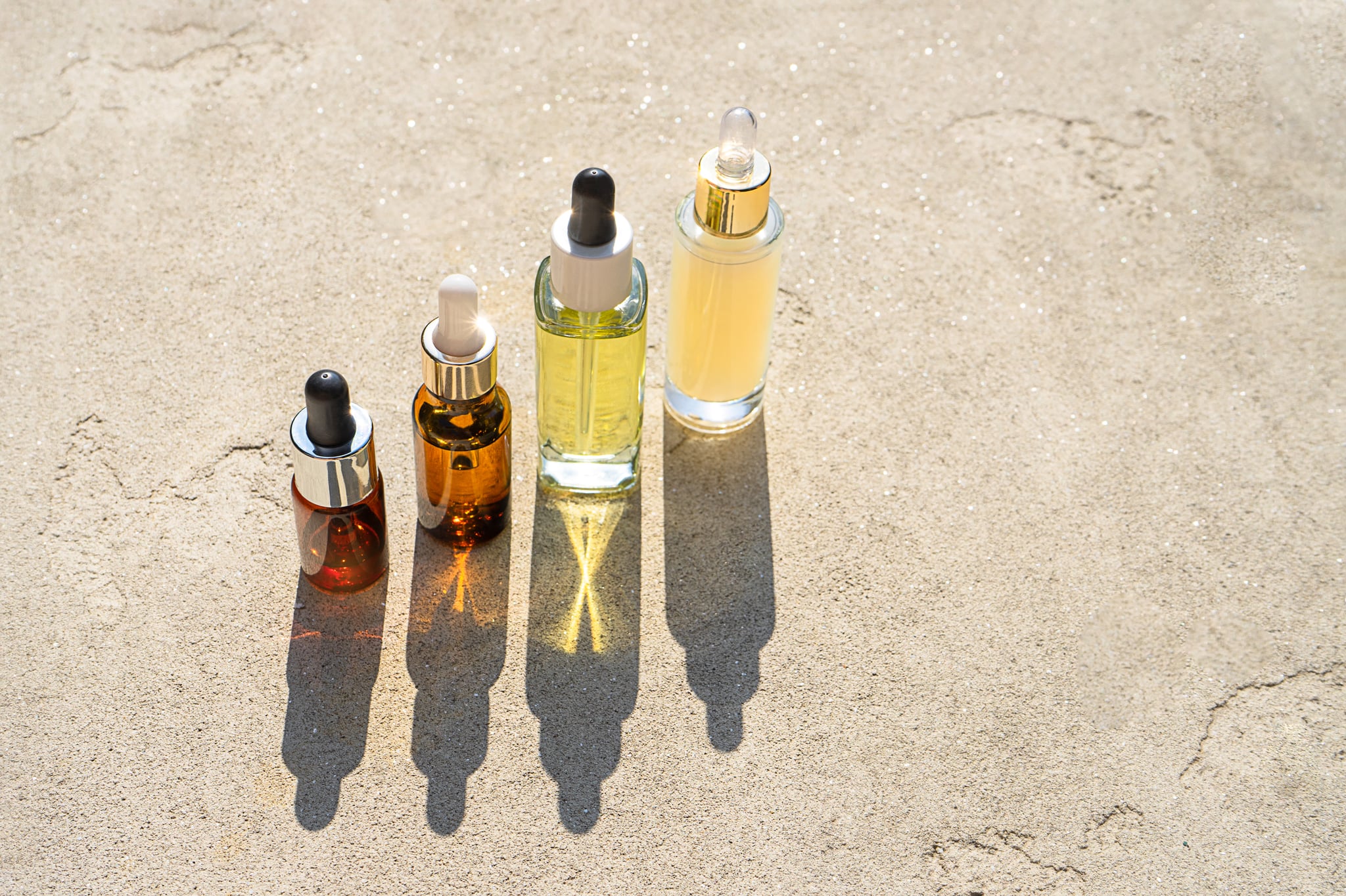 玻璃瓶美容精华液或油或乳液产品，在阳光下混凝土背景上有阴影。面部和身体必需的天然精油。有机的最小布局。创造性的概念。