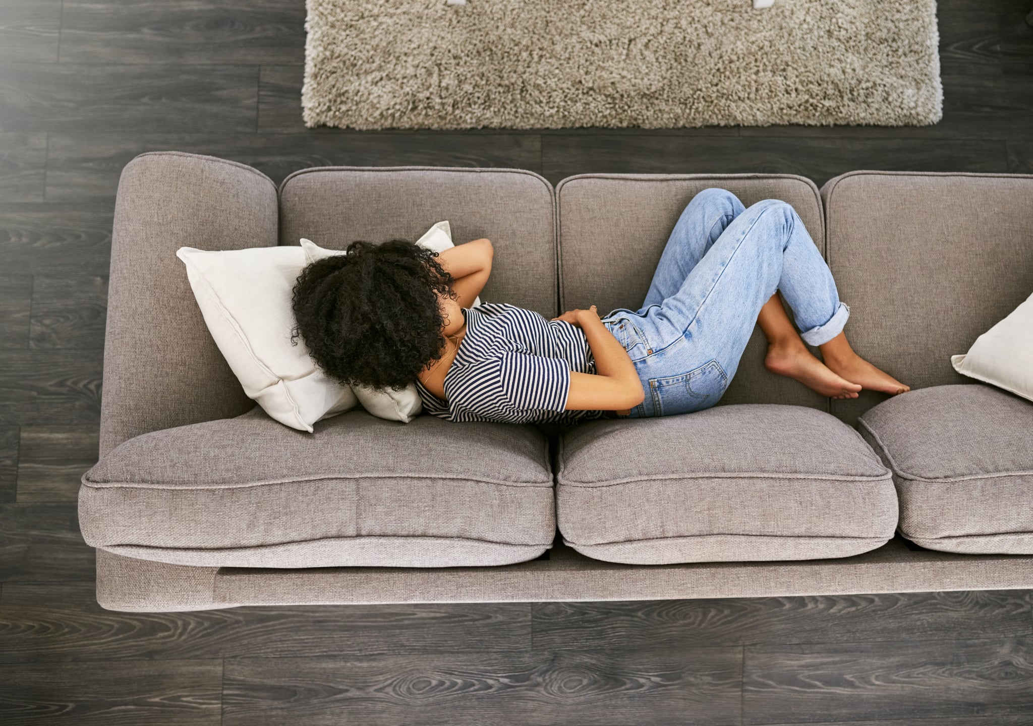 High angle shot of a young woman experiencing stomach pain on the sofa at home