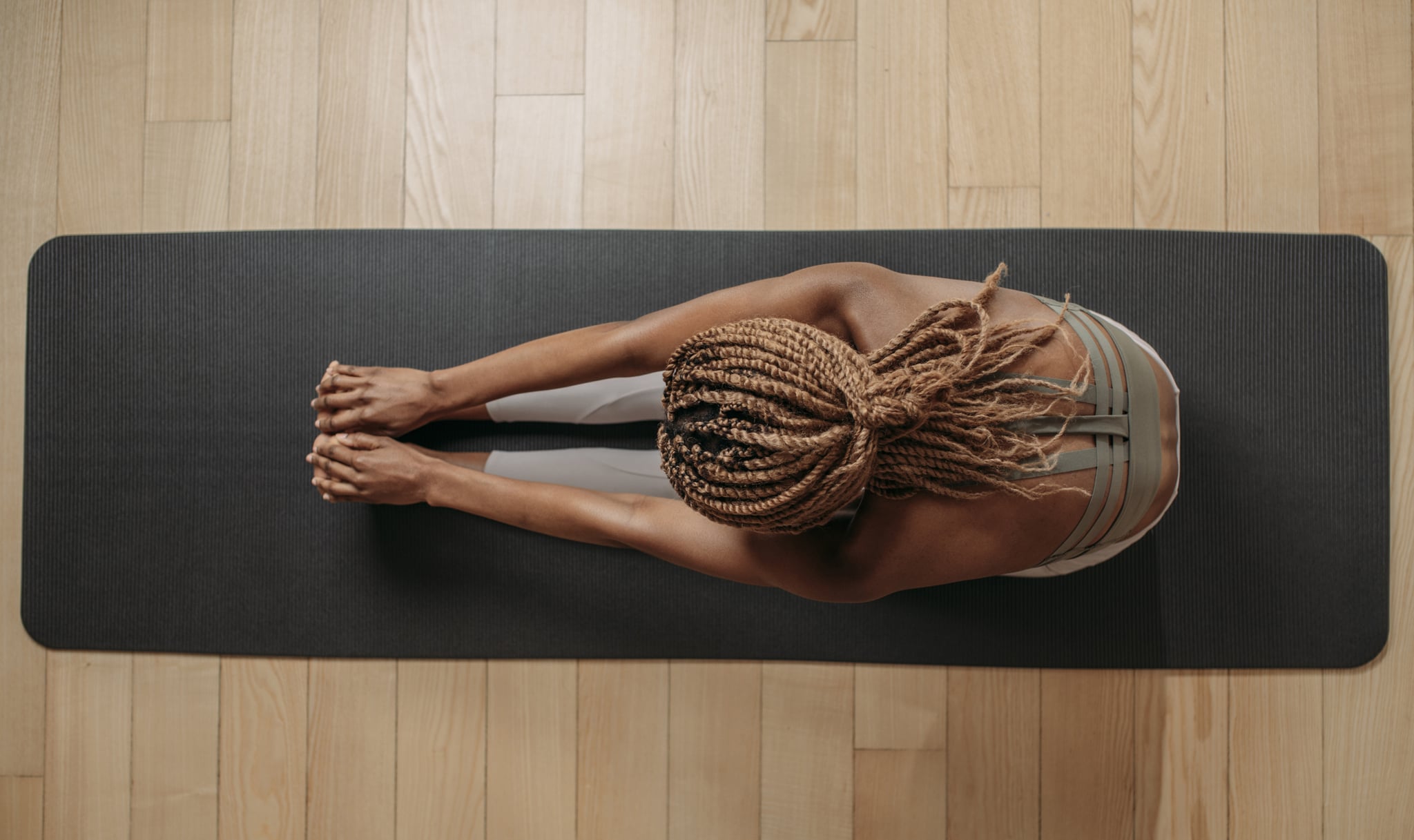 Overhead photo of sportswoman doing stretching exercise on fitness mat.