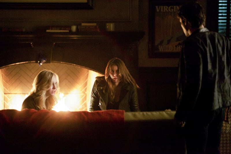 Caroline (Candice Accola) relaxes (ha, not really) by the fire with Elena.