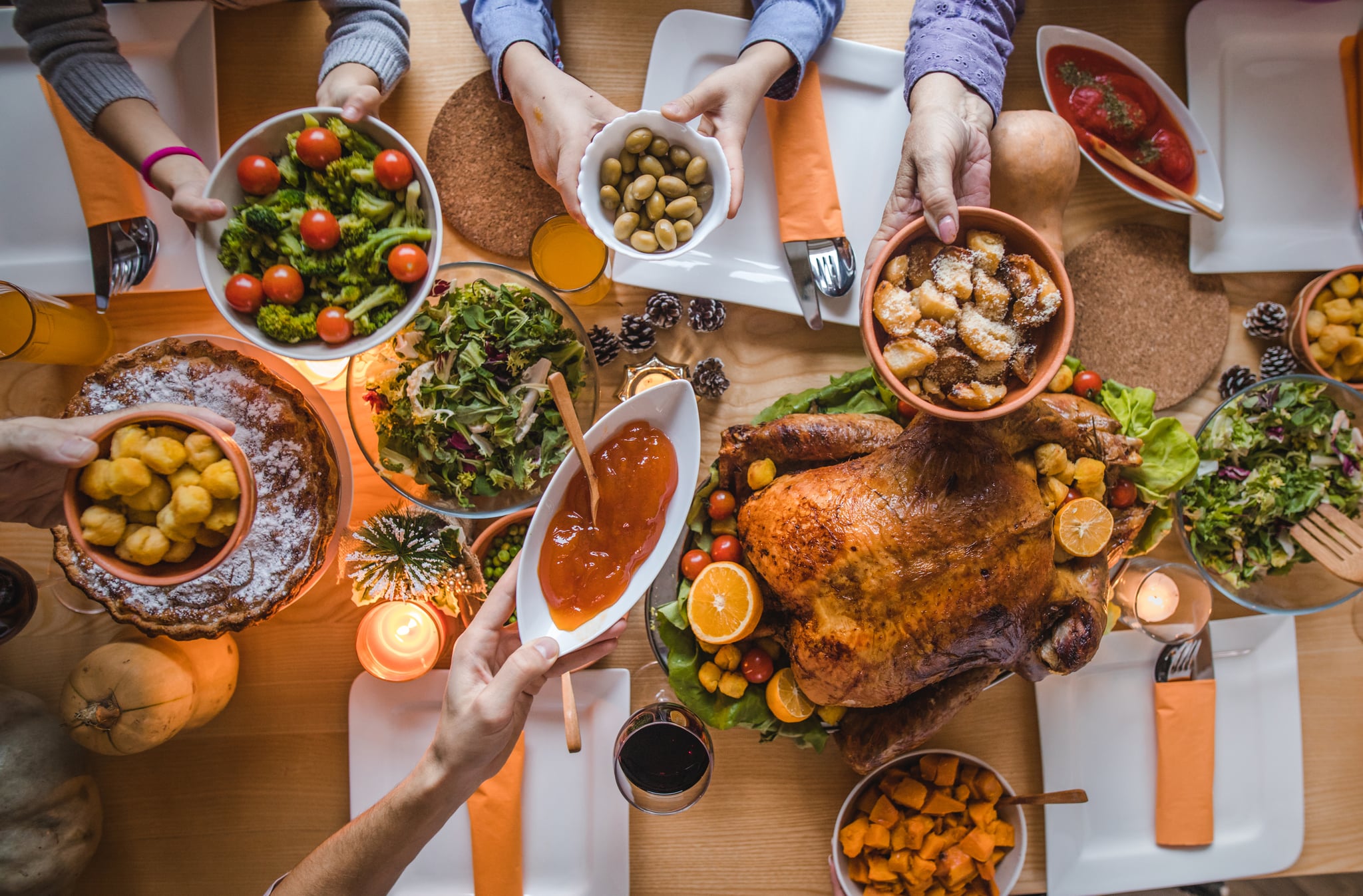 High angle view of unrecognisable people passing side dishes during Thanksgiving dinner at dining table.