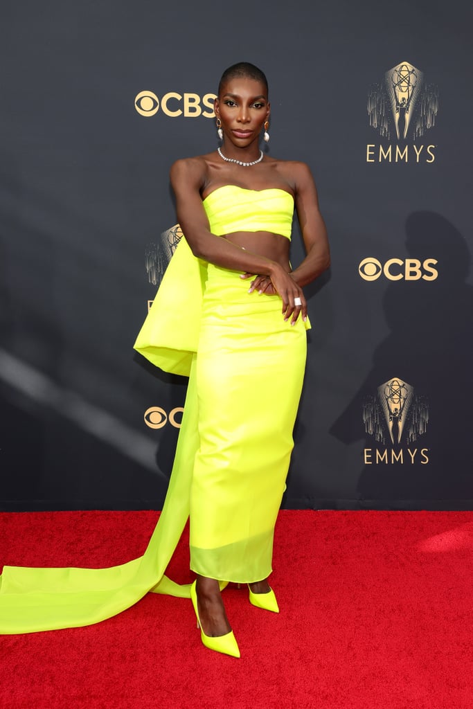 Celebrities were racing down the 2021 Emmys red carpet in looks so glamorous we were afraid to blink, but Michaela Coel reminded us all to yield and take in the moment with her neon yellow Christopher John Rogers two-piece dress. The custom look was composed of an ankle-length column skirt in cotton twill and a neon bralette top that transformed into an enormous six-foot silk organza bow from behind, flowing onto the ground like the vibrant train of a wedding dress. The I May Destroy You creator star didn't hesitate to go all in with the monochrome style statement and paired the look with highlighter yellow heels that made the entire look that much more electric. 
"Thank you to my FABULOUS team for turning this out impeccably!" designer Christopher John Rogers wrote on Instagram. Admire Michaela's look, styled by Zerina Akers, from all angles ahead. 

    Related:

            
            
                                    
                            

            I’m Just Really Digging Anya Taylor-Joy’s Sexy, Backless Take on Belle’s Ball Gown